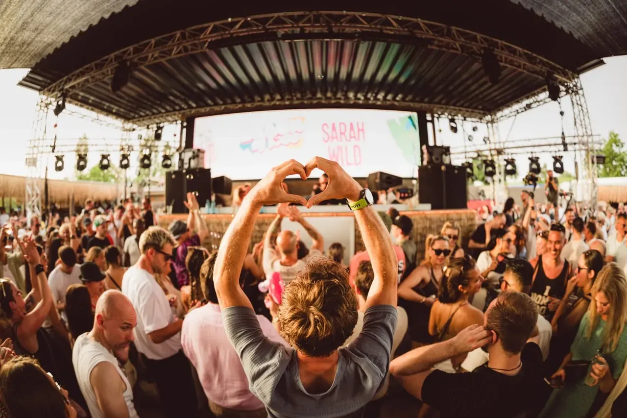 Gast formt mit den Händen ein Herz vor der Bühne der Beach of Love